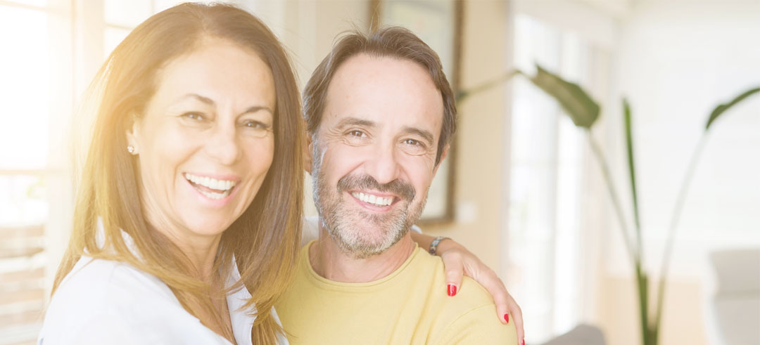 Pareja sonriendo mientras la mujer abraza al hombre
