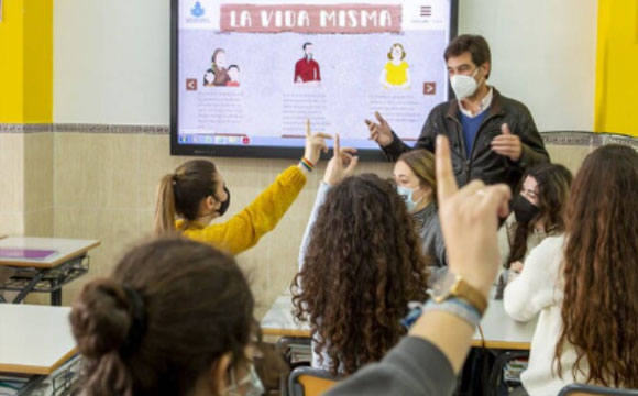 profesor en clase con alumnos levantando la mano