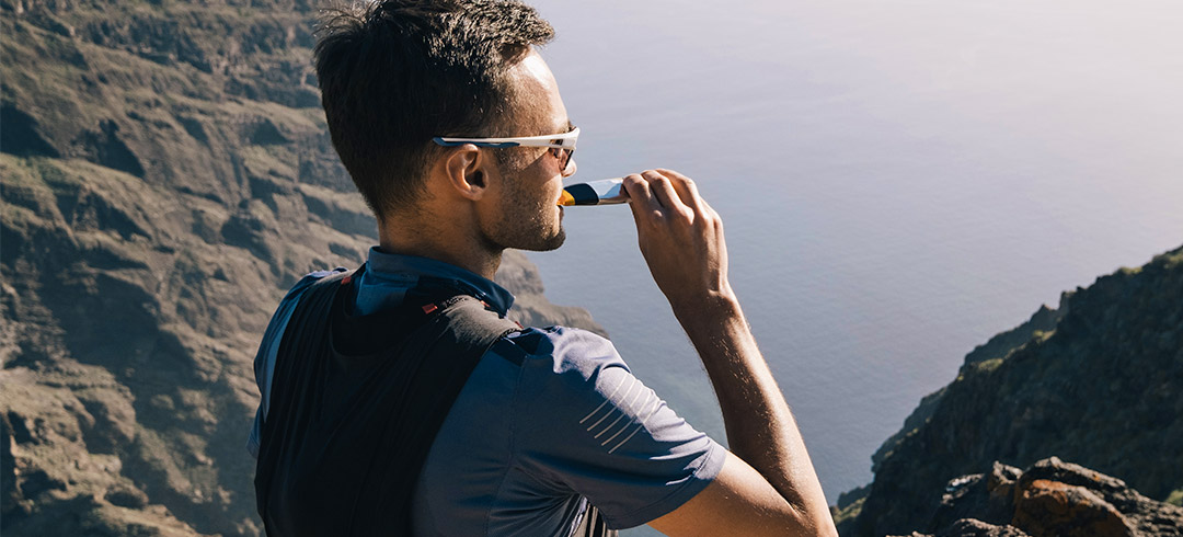 Hombre tomándose un gel energético arriba de una montaña