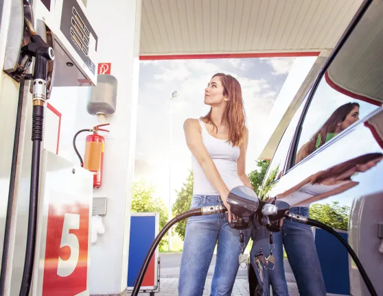 Mujer echando gasolina en el coche en un gasolinera