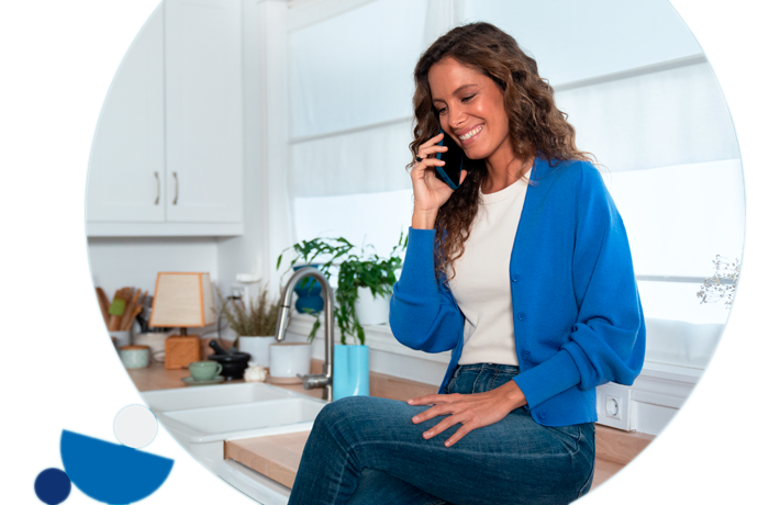 chica sonriente, entada en el mueble de la cocina, hablando por teléfono