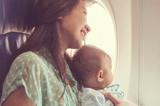 Mujer con un bebe en brazos sentada en un avión
